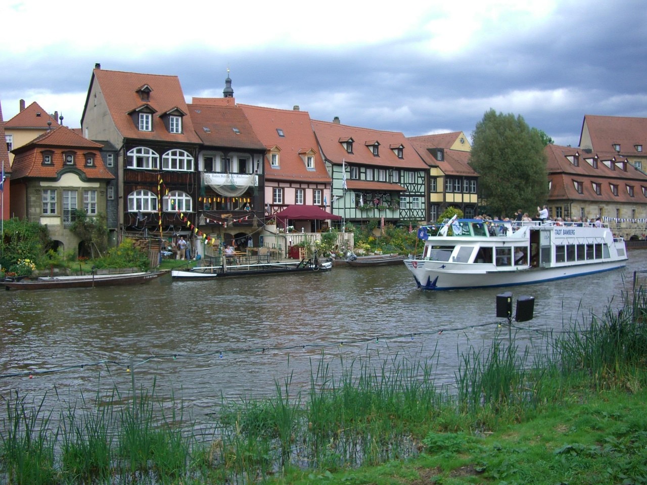 A tranquil river with a single boat gliding through the calm waters under a clear sky