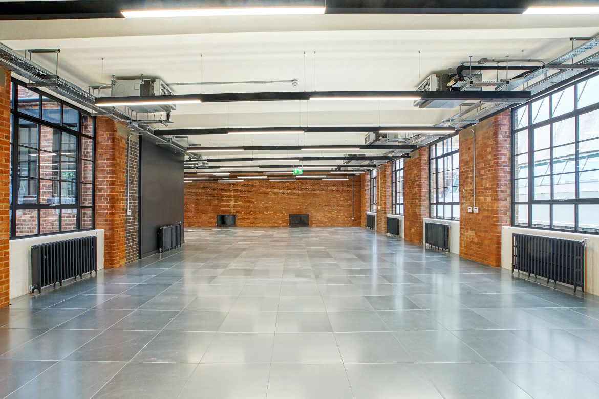 An empty office space featuring a large, exposed brick wall, creating a minimalist and industrial atmosphere